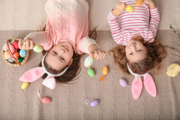 小さな女の子でウサギの耳とともにイースターの卵が家に横たわっています トップビュー — ストック写真