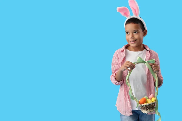 青い背景にイースターエッグのバスケットとウサギの耳の小さなアフリカ系アメリカ人の少年 — ストック写真