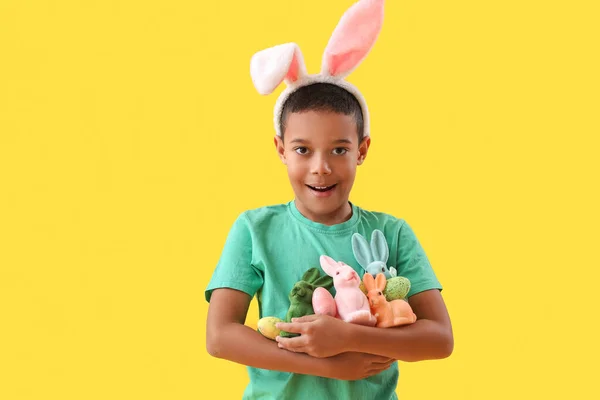 黄色の背景にイースターエッグとウサギを持つ小さなアフリカ系アメリカ人の少年 — ストック写真