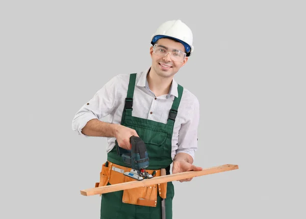 Young Carpenter Sawing Wooden Plank Grey Background — Stock Photo, Image