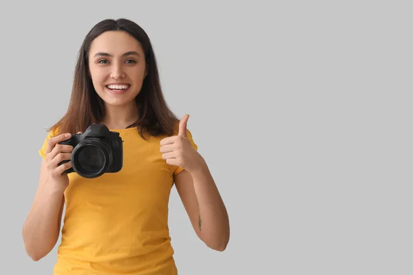 Vrouwelijke Fotograaf Met Professionele Camera Met Duim Grijze Achtergrond — Stockfoto