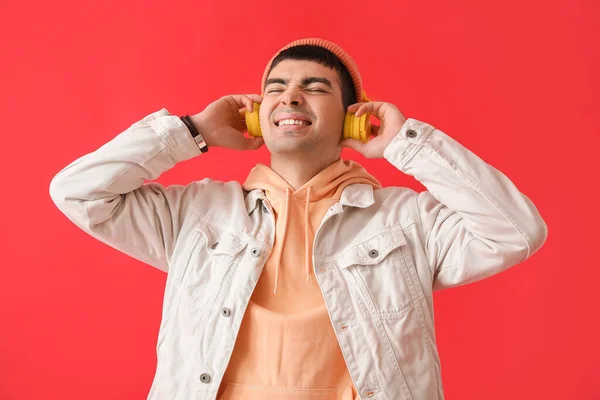 Szczęśliwy Młodzieniec Słuchawkach Słuchający Muzyki Czerwonym Tle — Zdjęcie stockowe