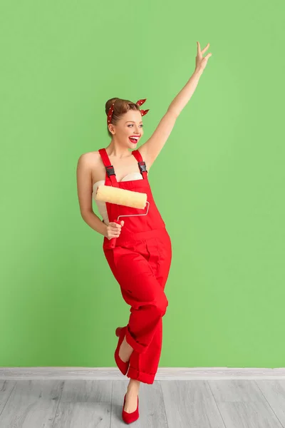 Mladý Pin Žena Červené Uniformě Nátěrem Váleček Zelené Stěny — Stock fotografie