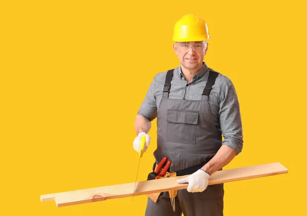 Reifer Tischler Sägt Holzplanke Auf Gelbem Hintergrund — Stockfoto