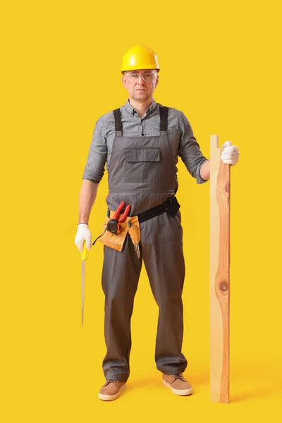 Reifer Tischler Mit Hacksäge Und Holzplanke Auf Gelbem Hintergrund — Stockfoto