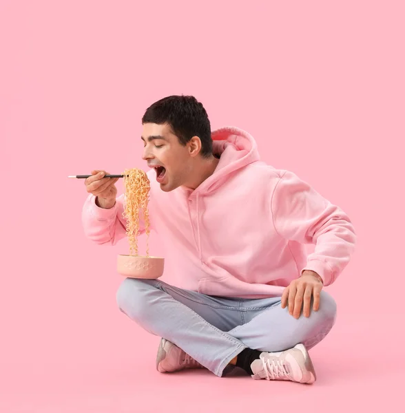Mladý Muž Jíst Čínské Nudle Růžovém Pozadí — Stock fotografie