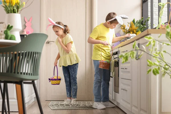 Little children looking for hidden Easter eggs in kitchen