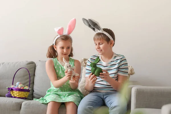 小さな子供たちは自宅でソファの上でイースターウサギと遊ぶ — ストック写真