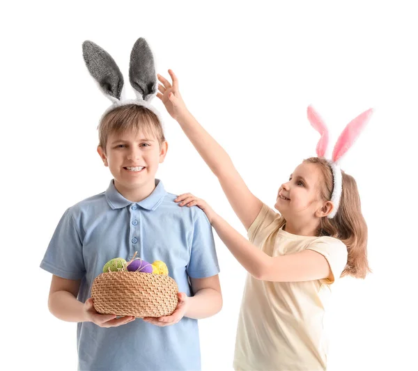 白い背景にイースターエッグのバスケットを持つウサギの耳の小さな子供たち — ストック写真