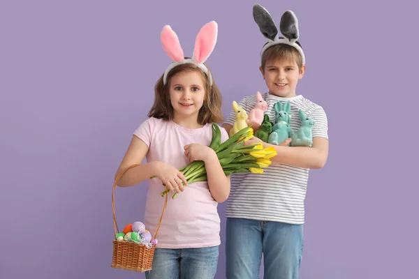 イースターエッグ おもちゃのウサギとライラックの背景にチューリップを持つウサギの耳の中の小さな子供 — ストック写真