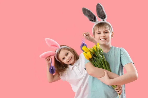 ピンクの背景に紙イースターエッグとチューリップとウサギの耳の中の小さな子供 — ストック写真