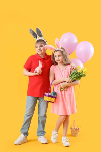 Kleine Kinderen Met Paaseieren Speelgoedkonijn Tulpen Ballonnen Gele Achtergrond — Stockfoto