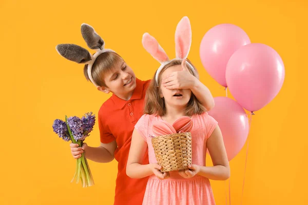 黄色の背景に妹の目を閉じる花を持つ小さな男の子 イースターのお祝い — ストック写真