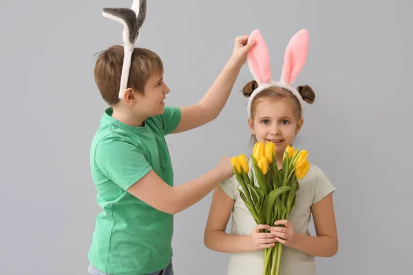 灰色の背景にチューリップを持つウサギの耳の中の小さな子供 イースターのお祝い — ストック写真