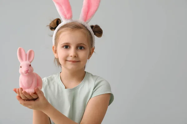 小さな女の子でウサギ耳とともにイースターウサギオングレー背景 — ストック写真