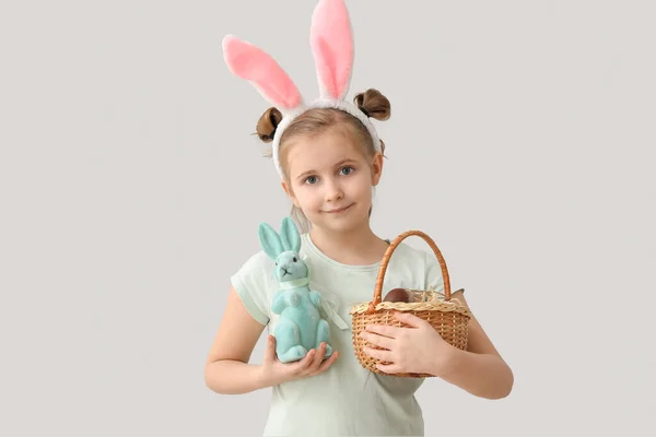 小さな女の子でウサギ耳とともにイースターウサギとバスケット上の灰色の背景 — ストック写真