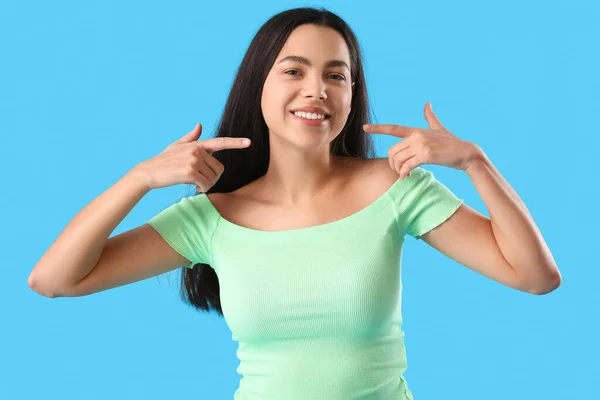 Güzel Genç Bir Kadın Mavi Arka Plandaki Gülüşünü Işaret Ediyor — Stok fotoğraf