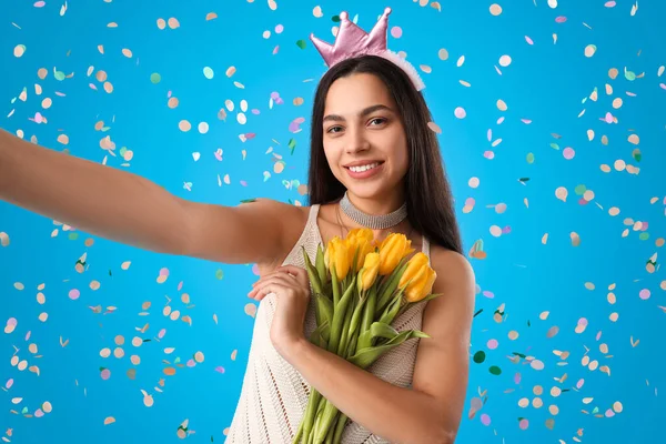 Happy young woman with tulips celebrating Birthday on blue background