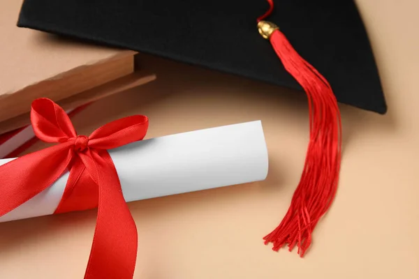 Kırmızı Kurdeleli Diploma Mezuniyet Şapkası Bej Arka Plan Kitapları — Stok fotoğraf
