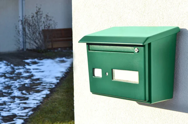 View of green mailbox on building wall, closeup
