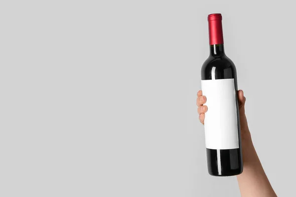 Vrouwelijke Hand Houden Fles Rode Wijn Grijze Achtergrond — Stockfoto