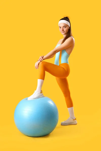 Sarı Arka Planda Fitball Oynayan Genç Bir Kadın — Stok fotoğraf