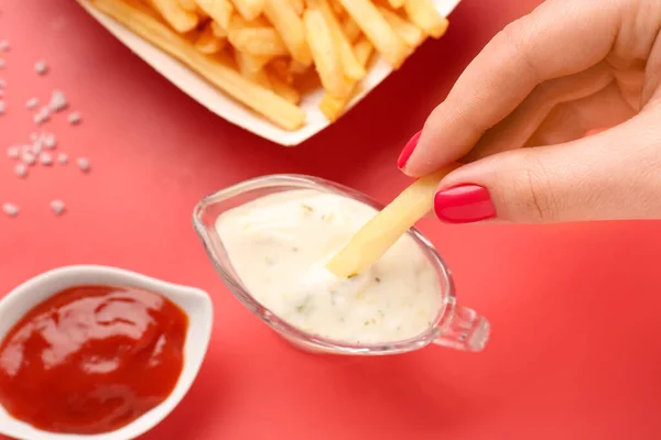 stock image Woman dipping french fries into mayonnaise on red background