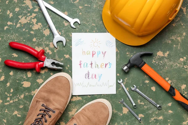 Card with text HAPPY FATHER\'S DAY, shoes and construction tools on grunge background