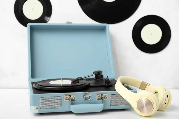 Record player with vinyl disk and headphones on white table