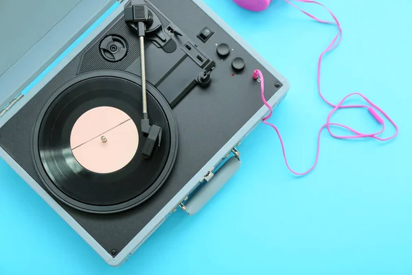 Record player with vinyl disk and headphones on blue background