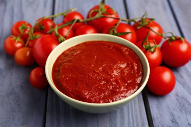 Mavi ahşap arka planda lezzetli domates ezmeli kase, yakın plan.
