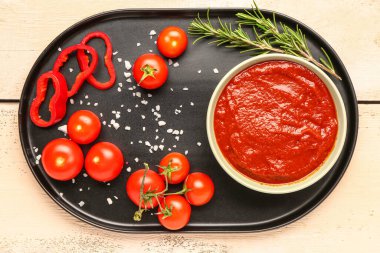 Lezzetli domates ezmesi ve hafif ahşap arka planda taze sebzeli kase.