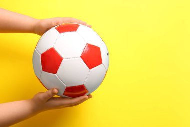 Sarı arka planda futbol topu olan eller