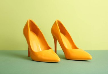 Yeşil arka planda şık topuklu ayakkabılar.