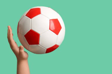 Turkuaz arka planda futbol topu olan bir çocuk eli