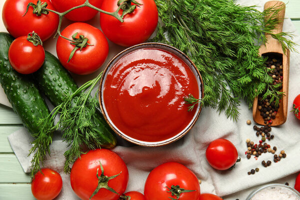Bowl with tasty ketchup and fresh vegetables on table, closeup