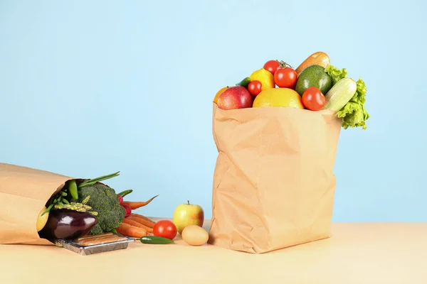 Paper bags with vegetables and fruits on table