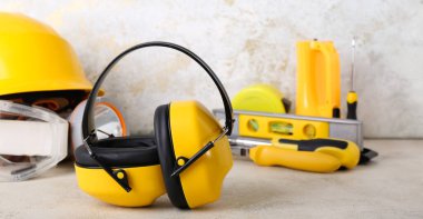 İşitme koruyucuları hafif arka planda inşaatçı araçları ile