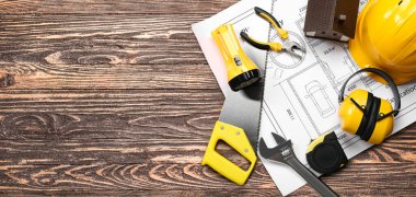 Ahşap arka planda inşa araçları ve işitme koruyucuları ile ev planı metin için alan