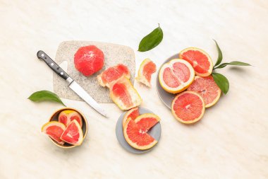 Açık arkaplanda kesilmiş greyfurtlar, kabuk ve bitki yaprakları ile bileşim