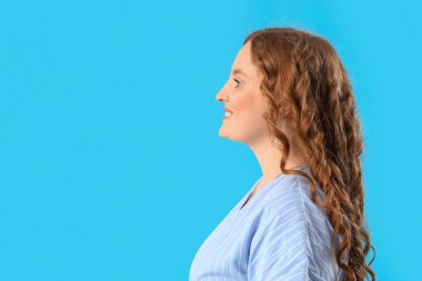 Mavi arka planda kızıl saçlı güzel bir kadın.