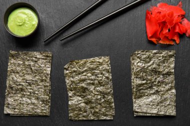 Slate board with nori sheets, zencefil, wasabi and chopsticks, close up