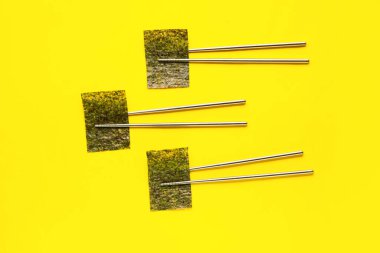 Sarı zemin üzerinde nori yaprakları olan çubuklar.