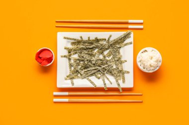 Renkli arkaplanda kesilmiş nori çarşafları, pirinci, zencefili ve çubuğu olan tabaklar