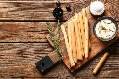Ahşap zemin üzerinde sos olan lezzetli İtalyan Grissini tablosu
