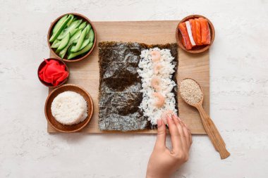Kadın arka planda suşi hazırlıyor.