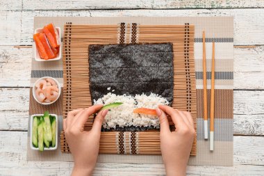 Suşi hazırlayan kadın hafif ahşap arka planda.