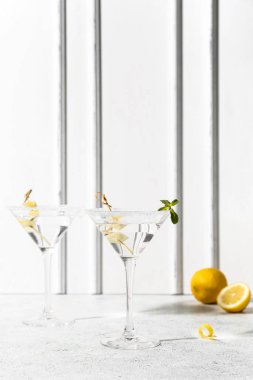 Beyaz masada bir bardak lezzetli martini ve limon.
