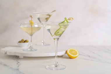 Beyaz masada bir bardak lezzetli martini ve limon.