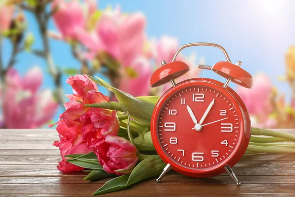 春の庭のテーブルの上にチューリップの花と目覚まし時計 — ストック写真